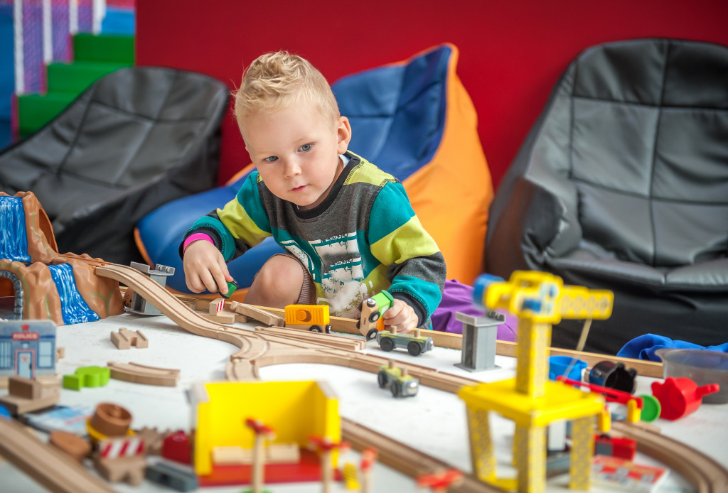 Toddler boy play with crane, train and cars